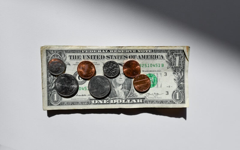 A dollar bill with coins on top. FAFSA and the return of SAT requirements is affecting many students' college applications.