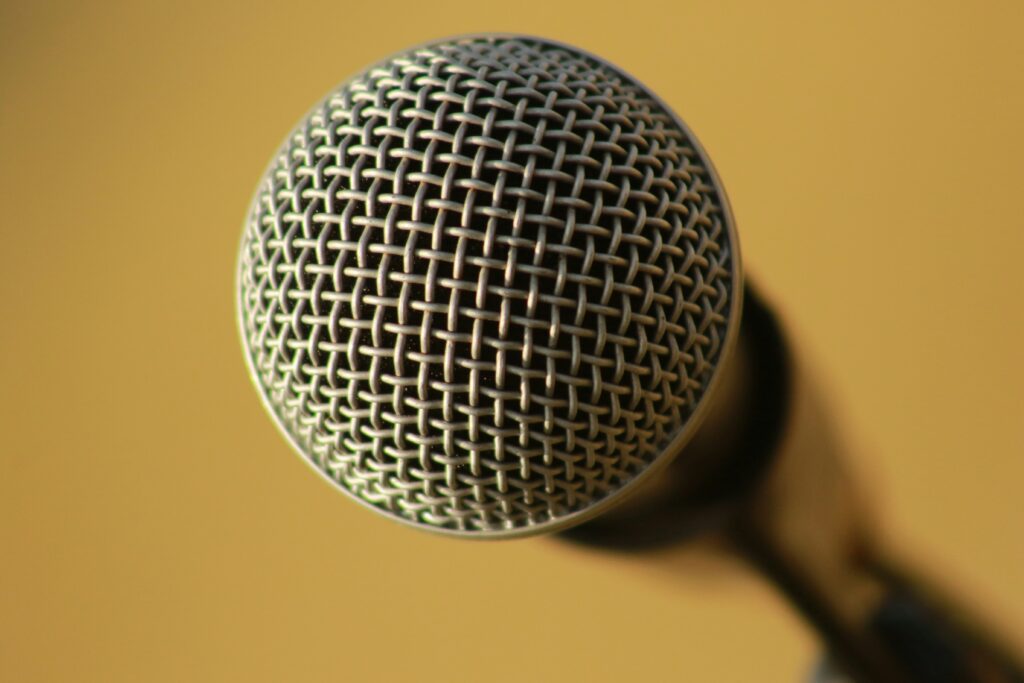 A microphone against a tan background. Want to know how to combat loneliness? Pursuing a shared hobby, like comedy, can help.